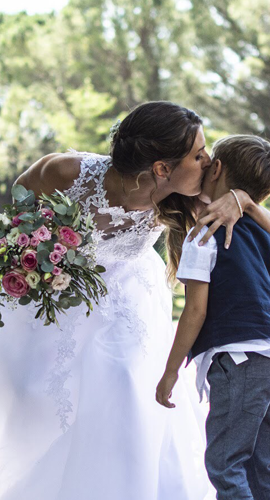 une mariée avec un bouquet de fleurs embrasse son enfant